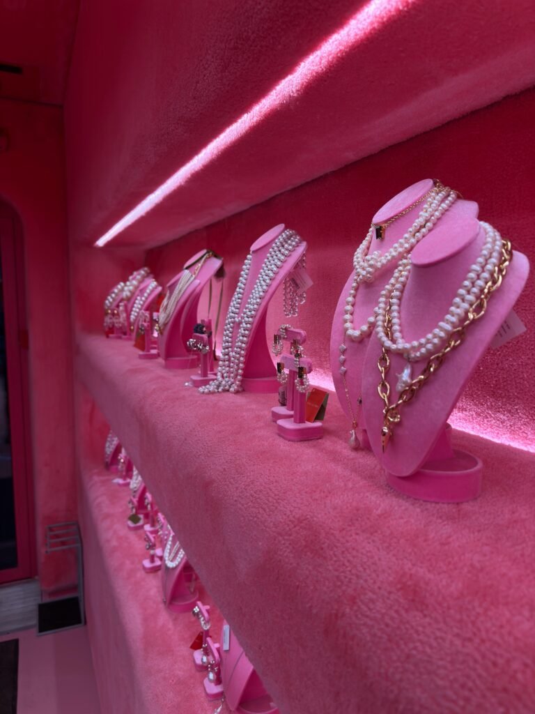 Stylish jewelry showcase with necklaces and rings on pink velvet stands.